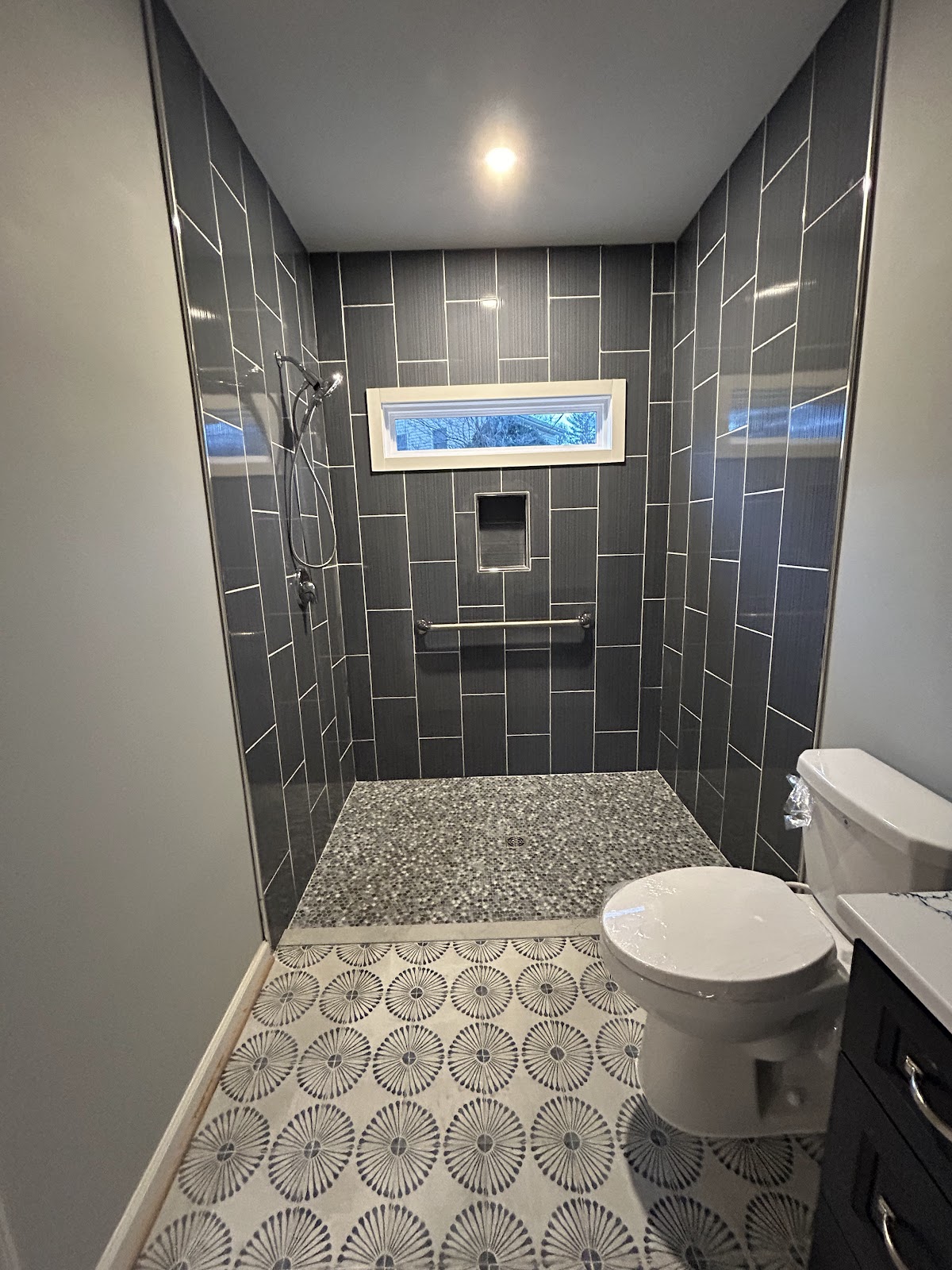Finished walk-in tile shower remodel with grab bar and pebble floor